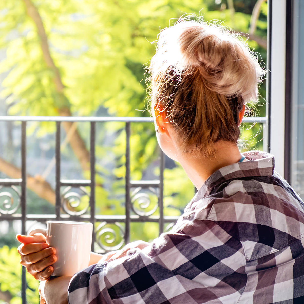 Cappella Pueblo West Senior Living Community in Pueblo West, CO - cappella of pueblo west woman with coffee looking out window