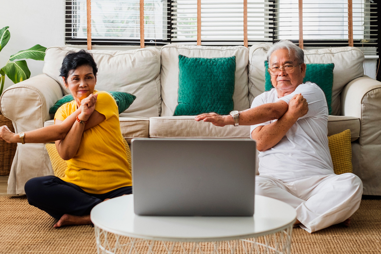 Cappella Pueblo West Senior Living Community in Pueblo West, CO - cappella of pueblo west couple doing yoga watching laptop computer